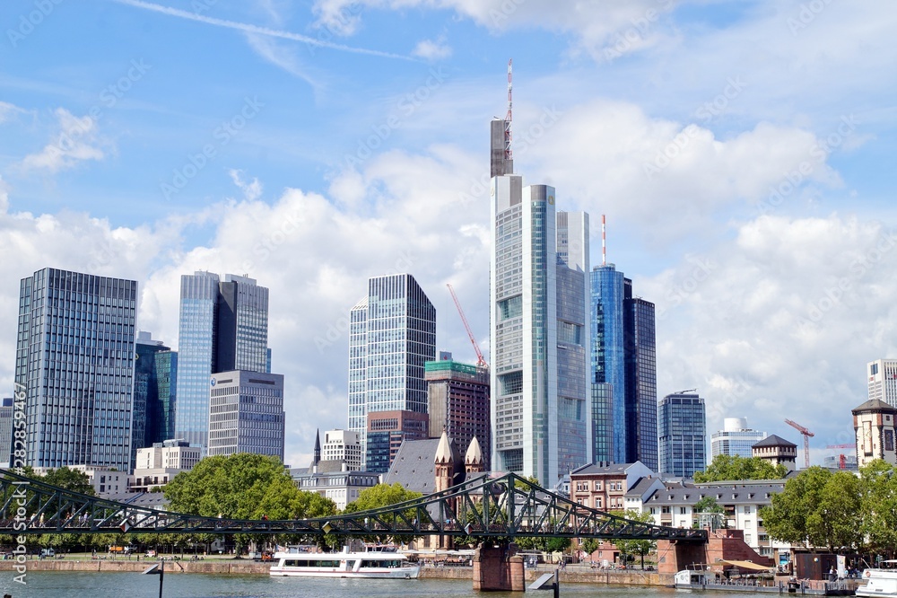 view of the river Main with the european city skyline and financial centre of Frankfurt. Skyscraper buildings in Germany on blue sky background. Business and finance concept