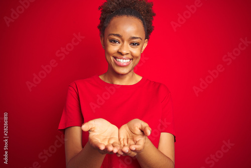 Fényképezés Young beautiful african american woman with afro hair over isolated red background Smiling with hands palms together receiving or giving gesture