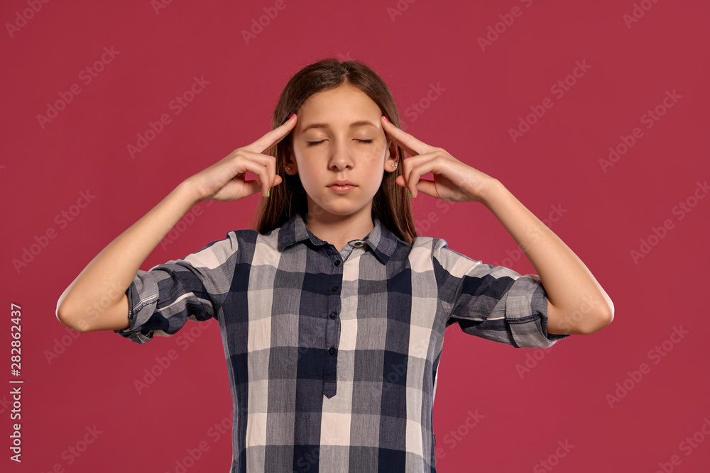 Beautiful teenage girl in a casual checkered shirt is posing against a pink studio background. Beautiful teenage girl in a casual checkered shirt is posing against a pink studio background.