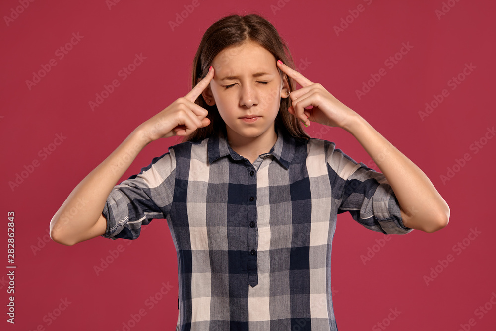 Beautiful teenage girl in a casual checkered shirt is posing against a pink studio background. Beautiful teenage girl in a casual checkered shirt is posing against a pink studio background.