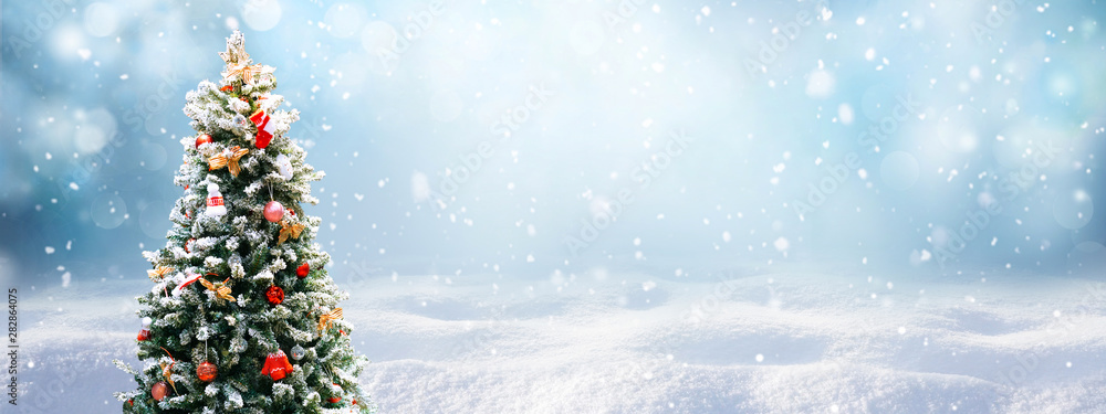 Plakat Piękne świąteczne świąteczne śnieżne tło. Choinka dekorująca z czerwonymi piłkami i trykotowymi zabawkami w lesie w zaspie w opadzie śniegu outdoors, sztandaru format, kopii przestrzeń.
