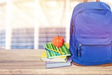 Blue school backpack with school supplies on wooden table
