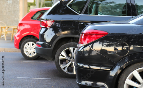 Closeup of rear, back side of black car with  other cars parking in outdoor parking area. © Amphon