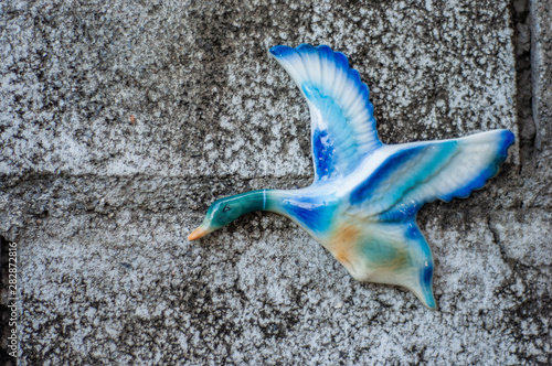 Ceramic flying duck blue and white on the concrete wall.
