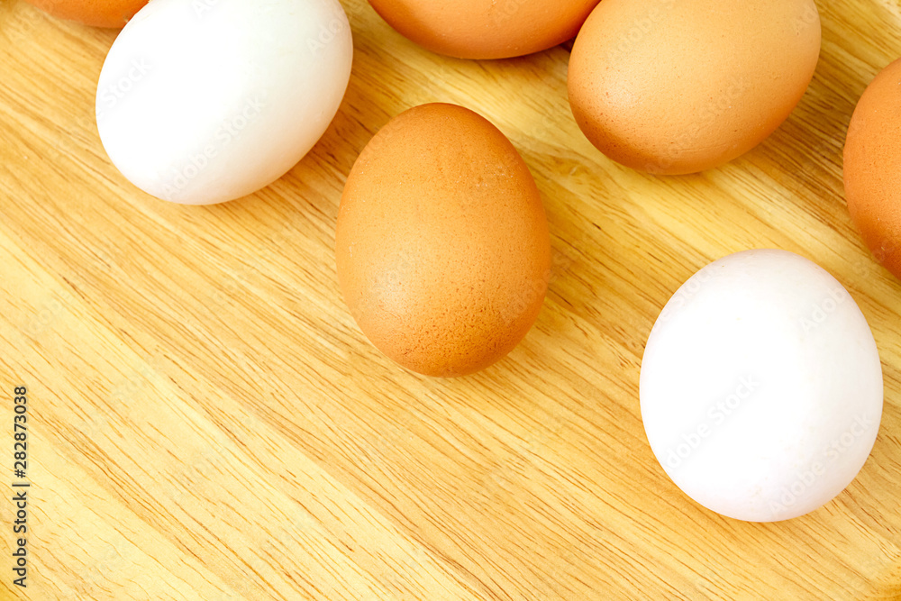 White and brown eggs on wooden background.