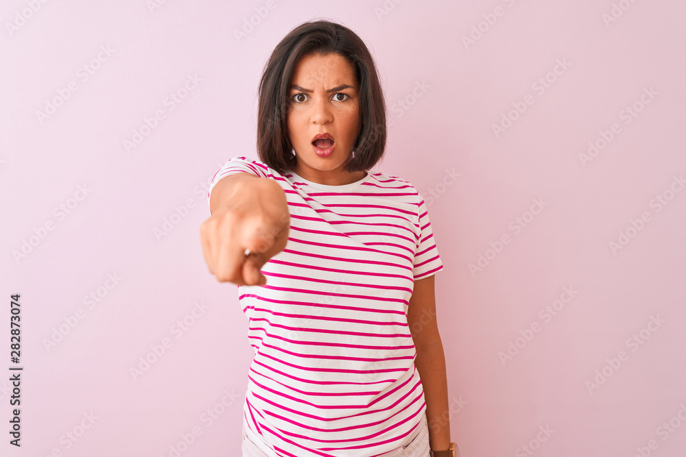 Young beautiful woman wearing striped t-shirt standing over isolated pink background pointing displeased and frustrated to the camera, angry and furious with you Young beautiful woman wearing striped t-shirt standing over isolated pink background pointing displeased and frustrated to the camera, angry and furious with you