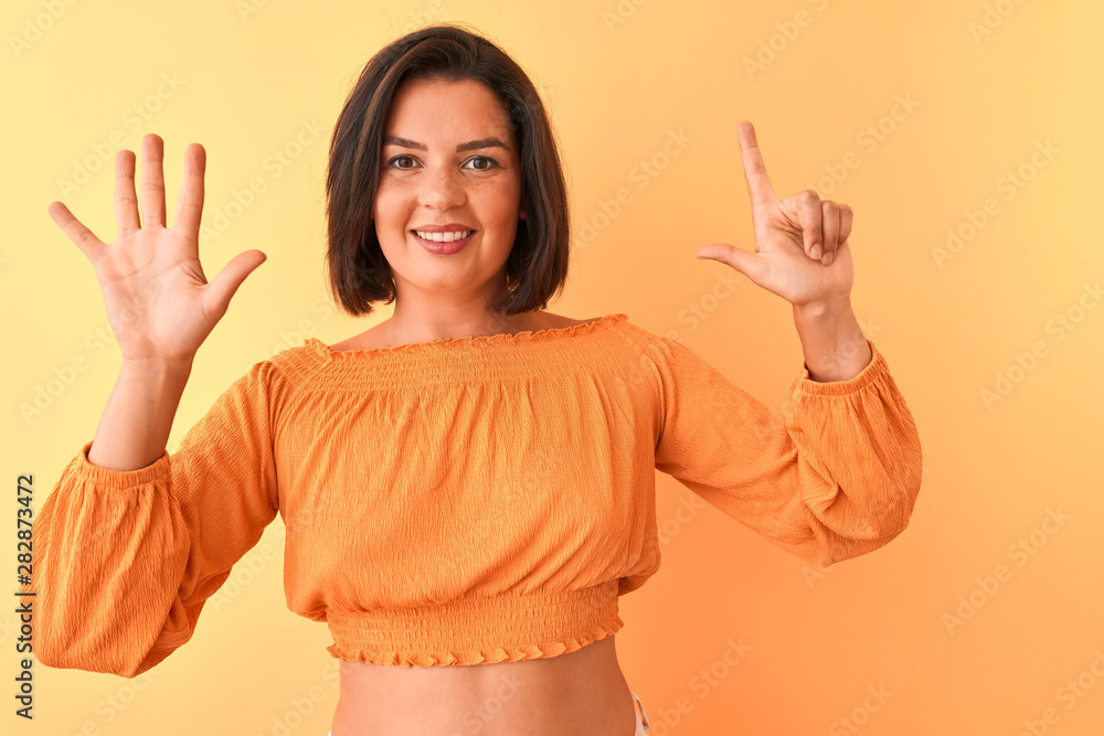 Young beautiful woman wearing casual t-shirt standing over isolated orange background showing and pointing up with fingers number seven while smiling confident and happy. Young beautiful woman wearing casual t-shirt standing over isolated orange background showing and pointing up with fingers number seven while smiling confident and happy.