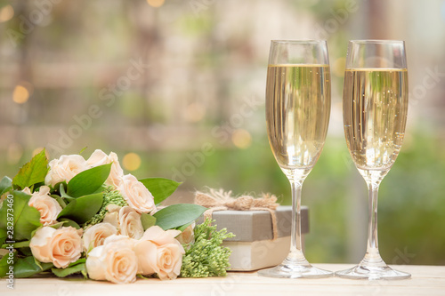 Rose flower, gift box, glass wine, on wooden table with bokeh background