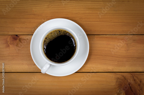 Cup of coffee on wood background, top view.