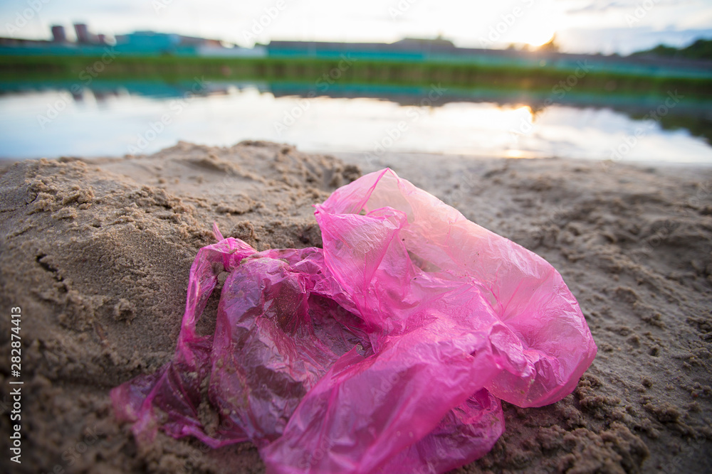 Cellophane package on the river bank. Environmental pollution.Garbage on the beach Cellophane package on the river bank. Environmental pollution.Garbage on the beach