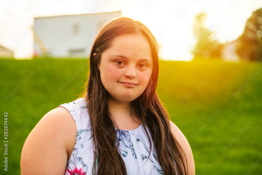 A Portrait of trisomie 21 adult girl outside at sunset A Portrait of trisomie 21 adult girl outside at sunset