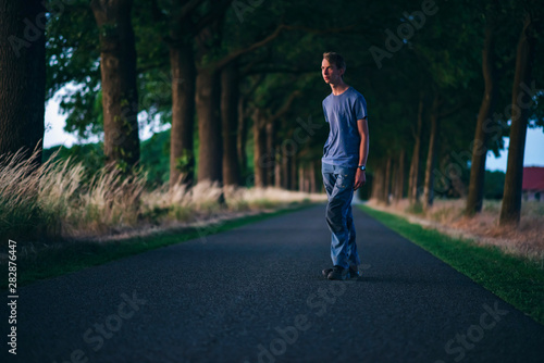 Young man on country road at sunset.
