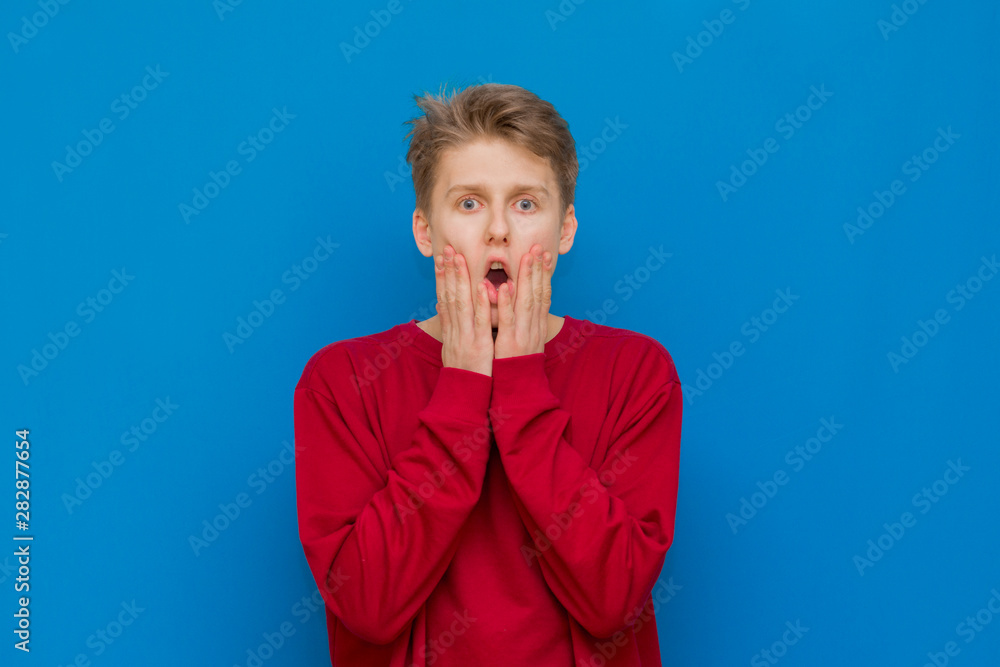 Anxious and insecure young teenage guy with curly hair in shirt biting ...