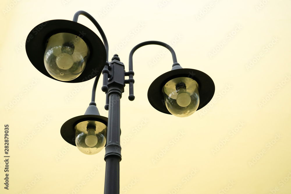 classic of three on one lamp pole with yellow background classic of three on one lamp pole with yellow background