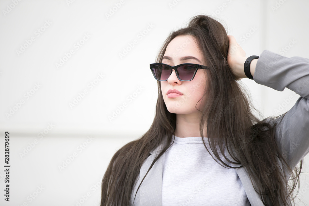 Beautiful young girl with long hair in sunglasses.Portrait of a Woman on the street