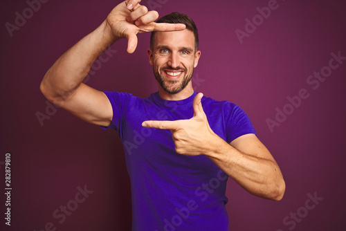 Young man wearing casual purple t-shirt over lilac isolated background smiling making frame with hands and fingers with happy face. Creativity and photography concept.