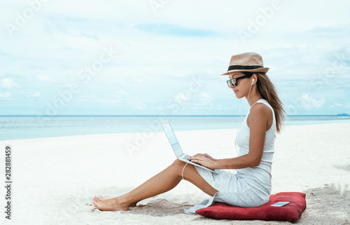 Young woman using laptop computer on a beach. Freelance  concept