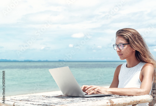 Young woman using laptop computer on a beach. Freelance  concept