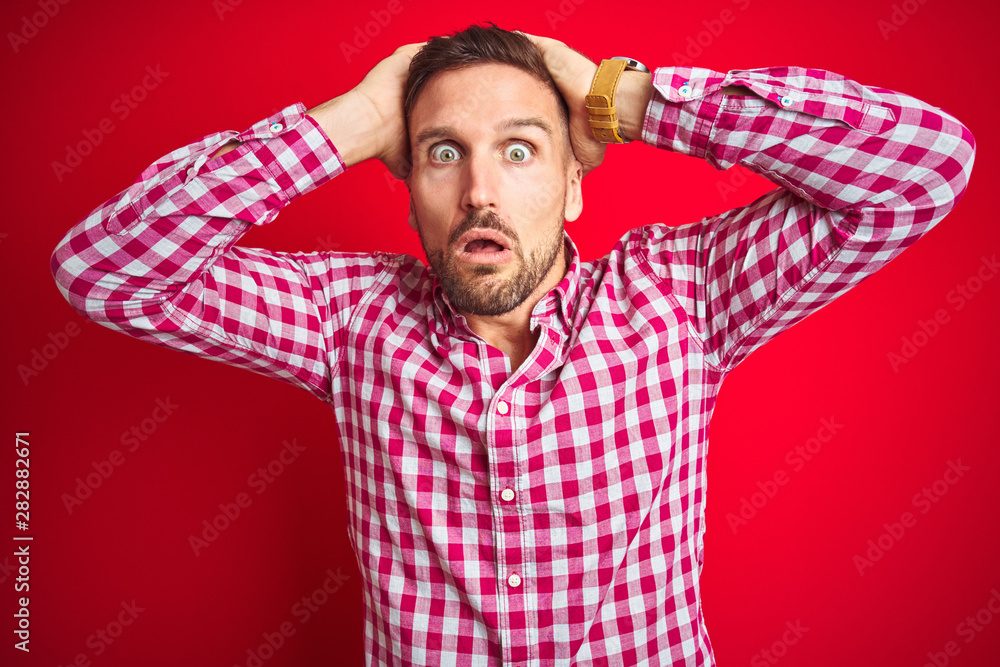 Young handsome man over red isolated background Crazy and scared with hands on head, afraid and surprised of shock with open mouth Young handsome man over red isolated background Crazy and scared with hands on head, afraid and surprised of shock with open mouth