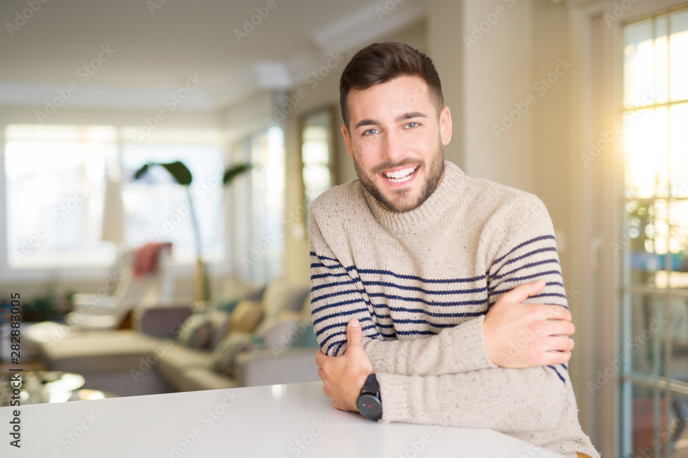 Fototapeta premium Young handsome man at home happy face smiling with crossed arms looking at the camera. Positive person.