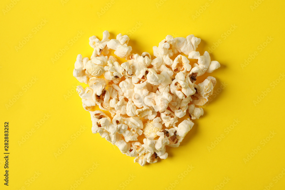 Flat lay composition with popcorn heart on yellow background, space for text