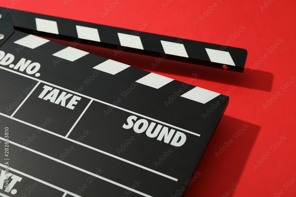 Black clapperboard on red background, space for text