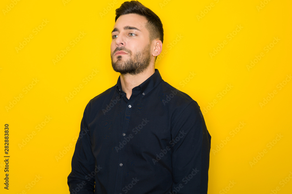 Obraz premium Young handsome man possing and modeling over yellow isolated background