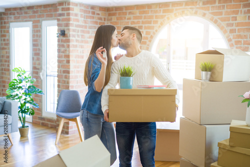 Young couple moving to a new home, hugging in love showing keys of new apartment smiling very happy