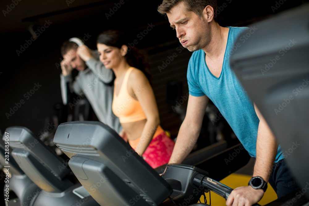 Young people using threadmill in modern gym Young people using threadmill in modern gym