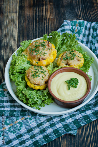 Baked Patty Pan Squash stuffed with meat and cheese, greens. Wood background.