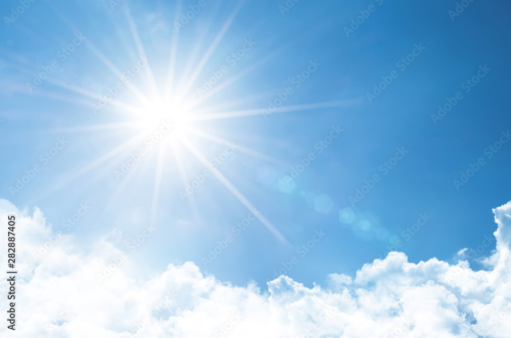 Clear sky with bright sun and rays in the atmosphere, below are light fluffy clouds.
