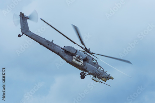 Military combat helicopter flies rapidly turning in the air.