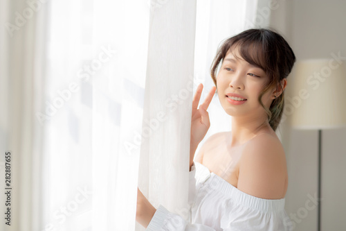 Portrait of beautiful young asian woman standing the window and smile while wake up with sunrise at morning, girl happy with freshness and cheerful, lifestyle and relax concept. Free Download Portrait of beautiful young asian woman standing the window and smile while wake up with sunrise at morning, girl happy with freshness and cheerful, lifestyle and relax concept. - GFXLoad