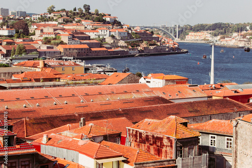 River Douro with embankment of Porto filtered. Porto panoramic landmark on sunny day. Old buildings with brick roofs by river Douro in Porto, Portugal. Historic district of Porto. Portuguese vacation.