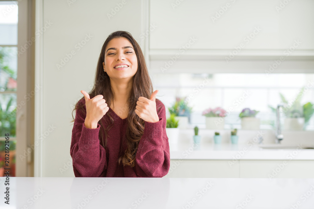 Young beautiful woman at home success sign doing positive gesture with hand, thumbs up smiling and happy. Looking at the camera with cheerful expression, winner gesture. Young beautiful woman at home success sign doing positive gesture with hand, thumbs up smiling and happy. Looking at the camera with cheerful expression, winner gesture.