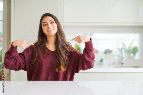 Young beautiful woman at home looking confident with smile on face, pointing oneself with fingers proud and happy. © Krakenimages.com