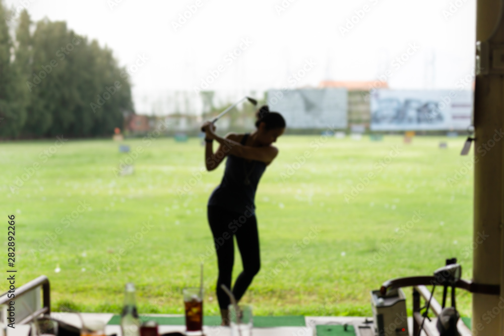 Blurred concept woman practicing his golf swing at the golf driving range.