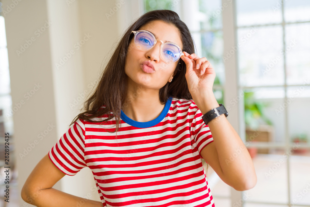 Beautiful young woman wearing glasses and posing sending a kiss and doing funny faces Beautiful young woman wearing glasses and posing sending a kiss and doing funny faces
