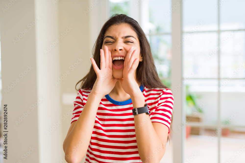 Beautiful young woman shouting and screaming with hand on mouth very excited Beautiful young woman shouting and screaming with hand on mouth very excited