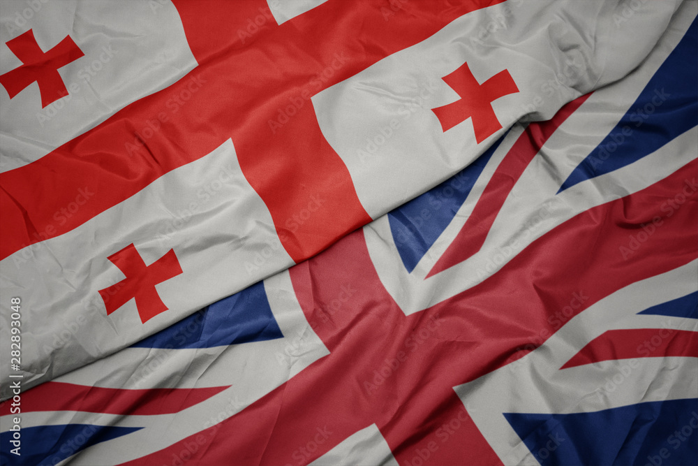 Fototapeta premium waving colorful flag of great britain and national flag of georgia.
