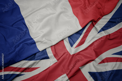 waving colorful flag of great britain and national flag of france.