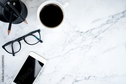 Marble table with smartphone, glasses and coffee in the top view. Modern business concept.