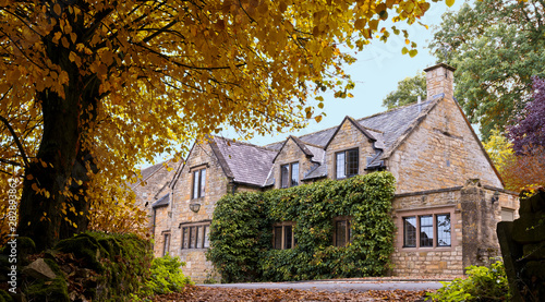 English Cotswold's Stone House and autumn colored trees.