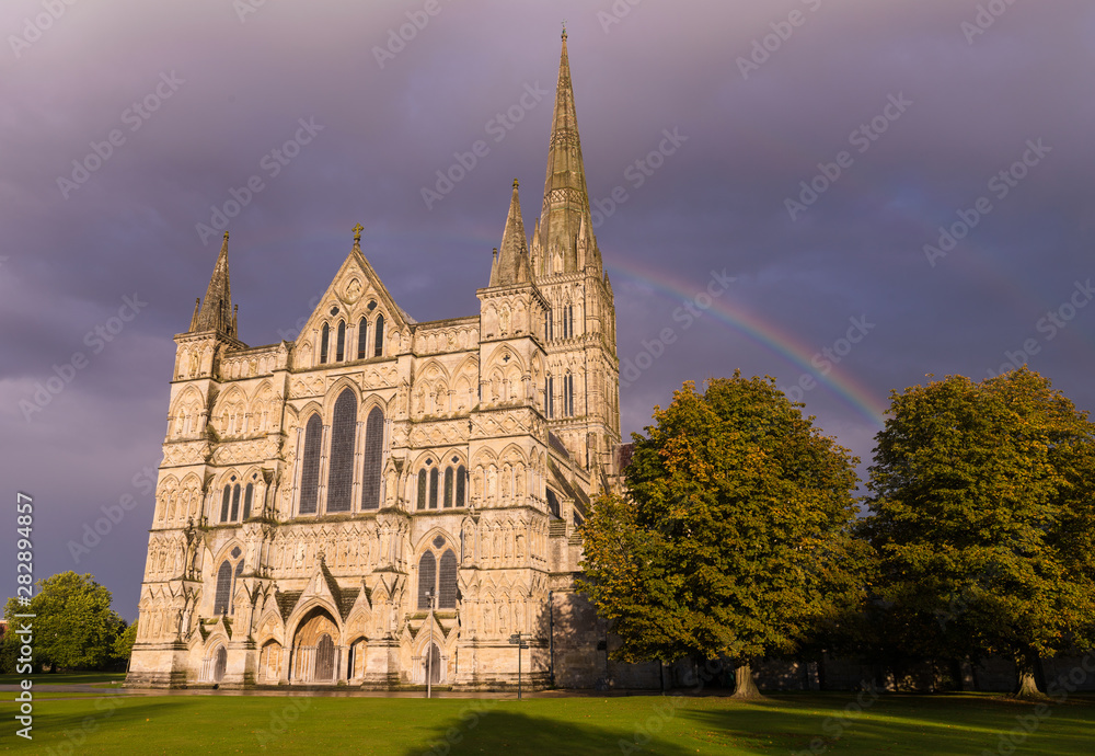 Salisbury Cathedral in England at Sunset with dark rain clouds and  rainbow
