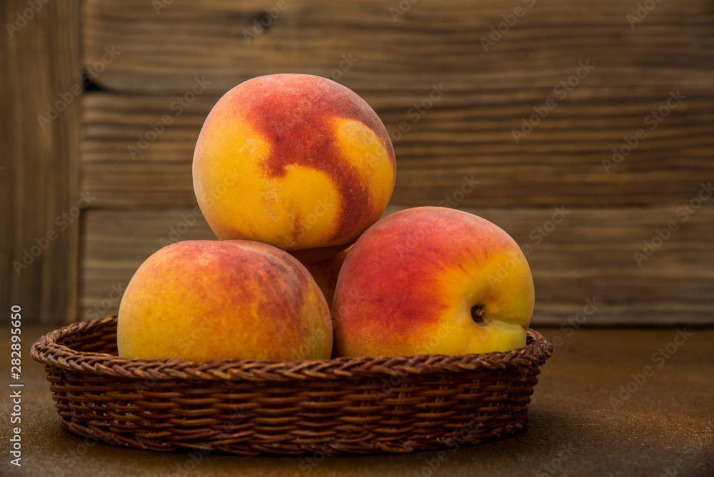 Peaches in a wicker basket on rustic background