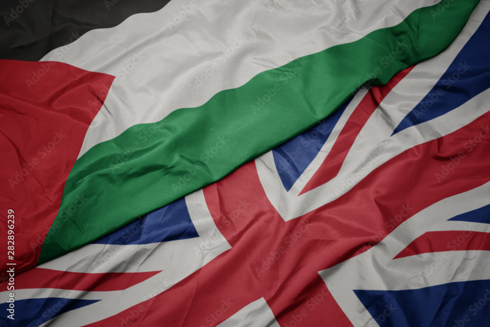 waving colorful flag of great britain and national flag of palestine.