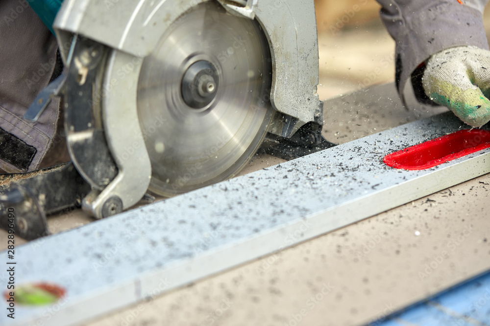 A construction contractor worker using a worm-driven hand-held circular saw to cut boards and plastic. Construction concept, own workshop, hiring a working contract for cutting wood. A construction contractor worker using a worm-driven hand-held circular saw to cut boards and plastic. Construction concept, own workshop, hiring a working contract for cutting wood.