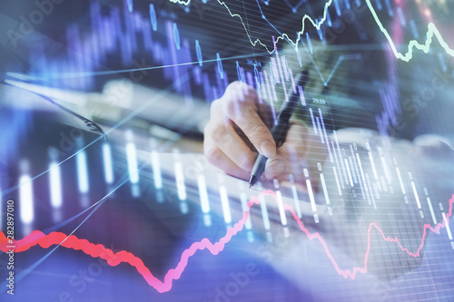 Financial forex graph displayed on hands taking notes background. Concept of research. Multi exposure