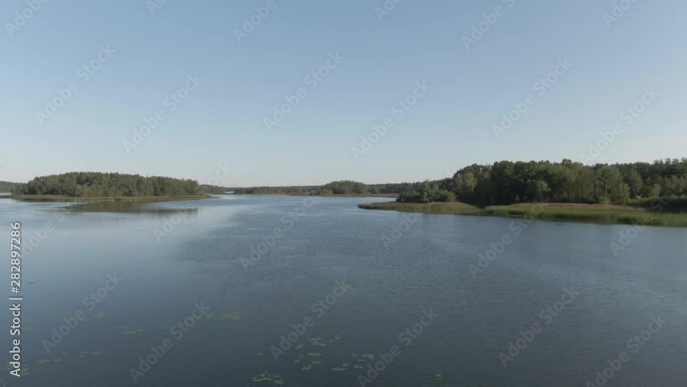 Flying over lake and island. River with ripples. Arial drone shot. Water and waves. Coast and wild forest. Flying over lake and island. River with ripples. Arial drone shot. Water and waves. Coast and wild forest.