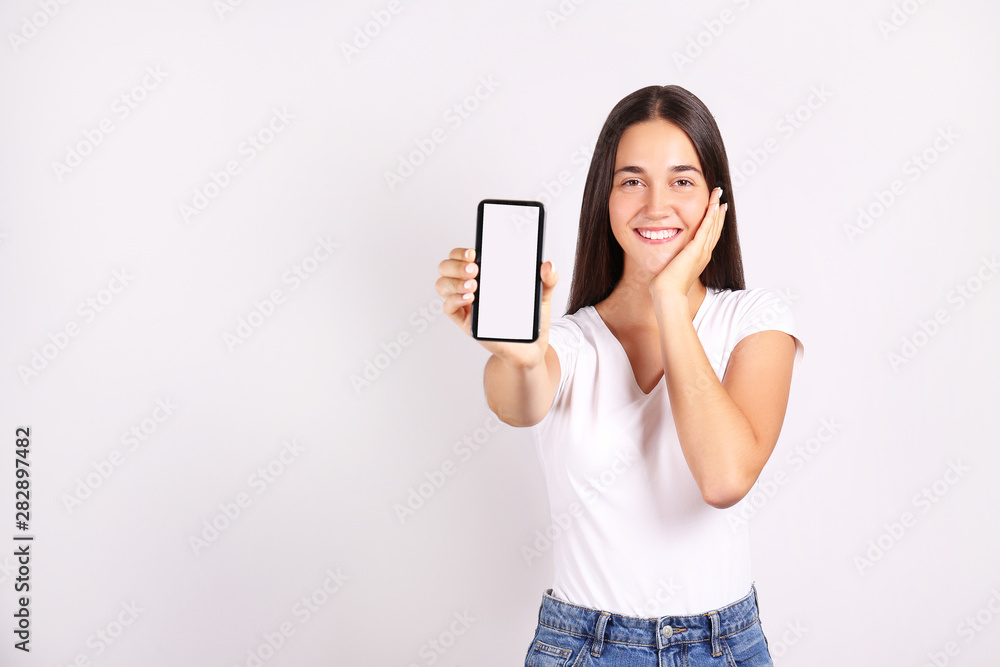 Young beautiful brunette woman w/ long black straight hair posing over bright colorful isolated background & holding smartphone. Portrait of teenage female model showing emotions. Close up, copy space Young beautiful brunette woman w/ long black straight hair posing over bright colorful isolated background & holding smartphone. Portrait of teenage female model showing emotions. Close up, copy space